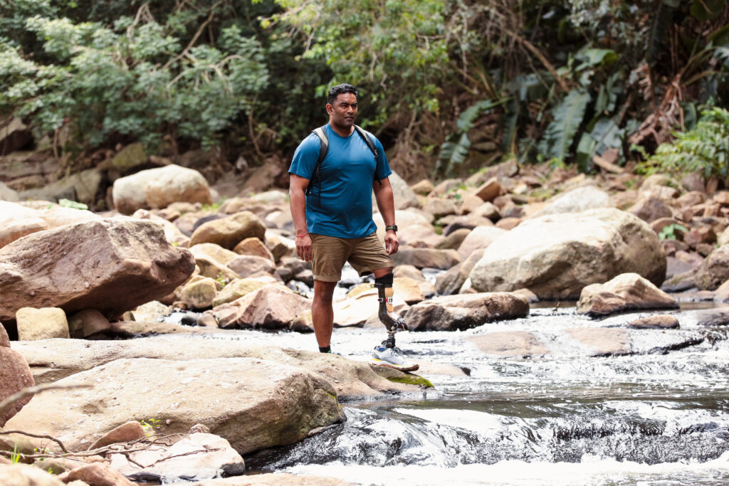 Fillauer AllStar Tyrone Pillay hiking near a river on an AllPro XTS.