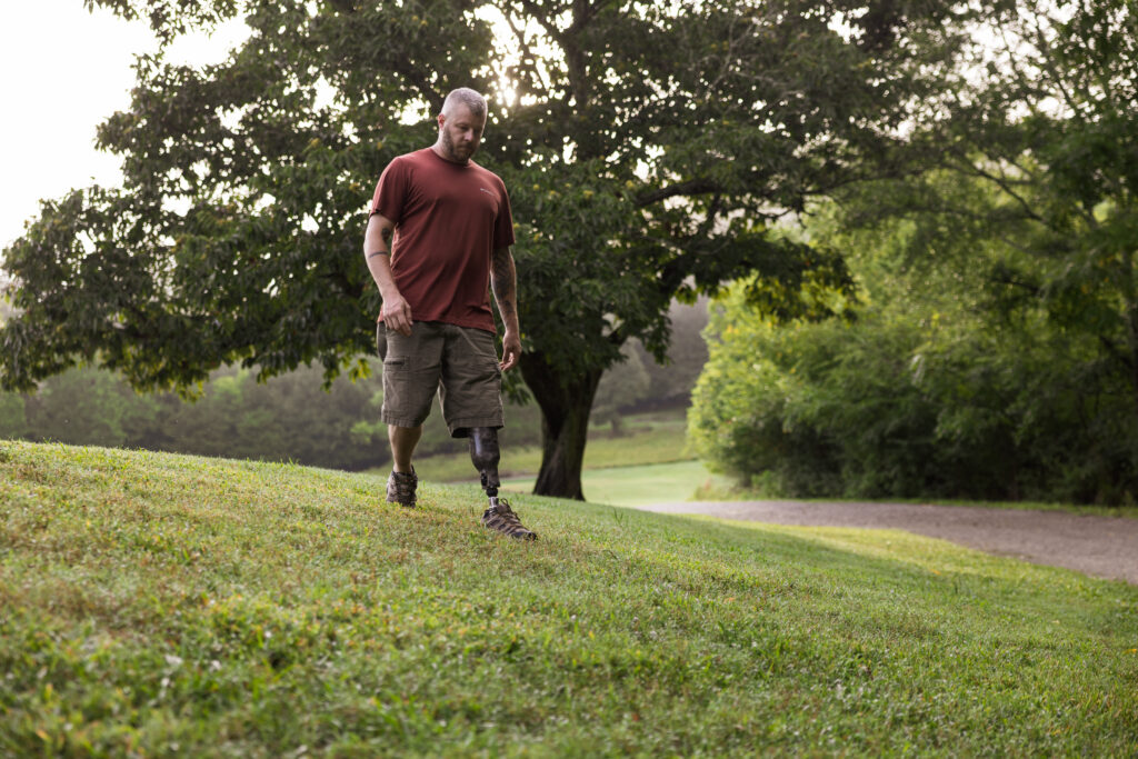 Man walking down wet, grassy slope wearing the Traverse AV