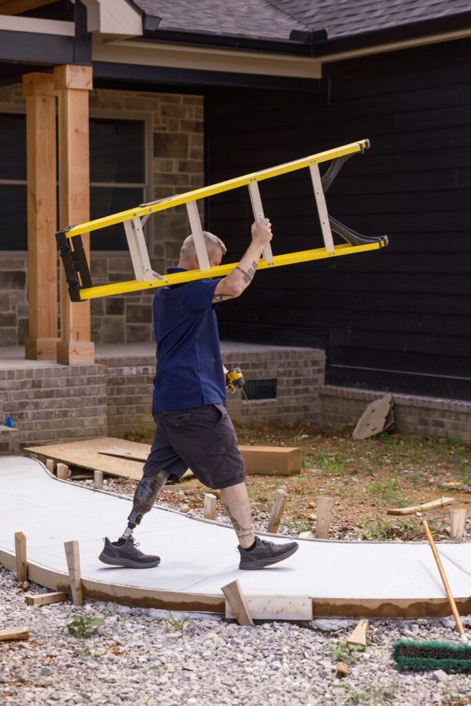 Man wearing Traverse AV carrying a ladder on a construction site