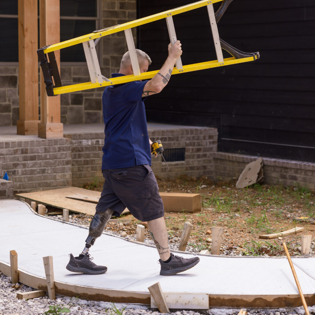 Man wearing Traverse AV carrying a ladder on a construction site