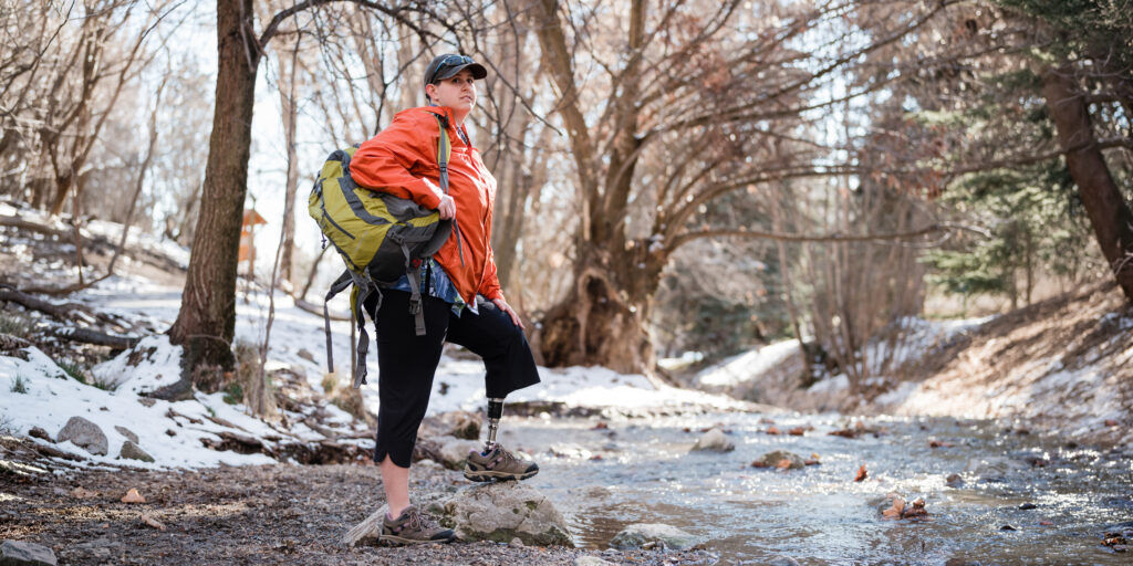 Woman wearing Traverse SLX on rocky, snowy terrain near a river